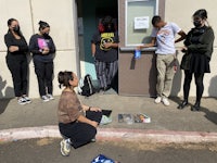 a group of people sitting on the ground in front of a building