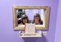 two girls looking at a mirror in a purple room